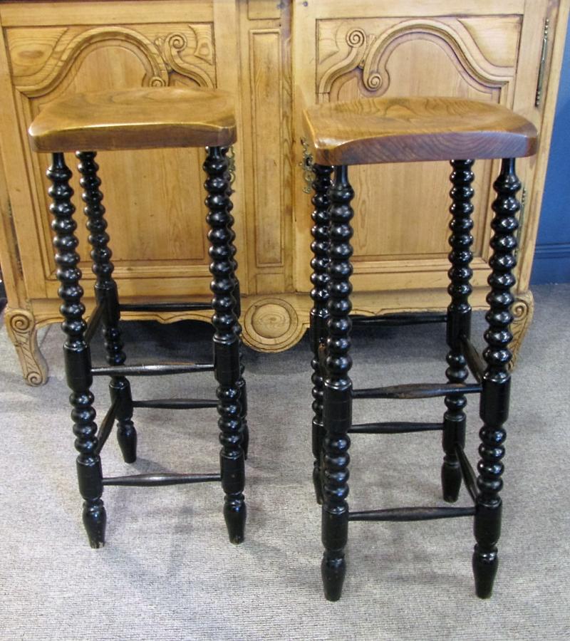 A pair of elm and ebonised counter stools
